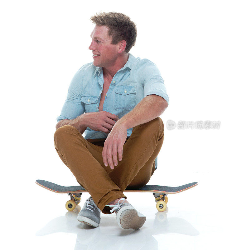 全长20-29岁英俊的人/短发白人男性/年轻男子滑板/滑板/滑冰/坐/坐在地板前的白色背景穿纽扣衬衫/裤子